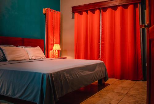 a bedroom with red curtains and a bed at Wild Arenal Village in Fortuna