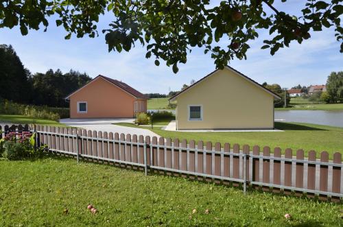 a fence in front of two houses and a pond at Pension Zum Grünen Wald in Feuchtwangen