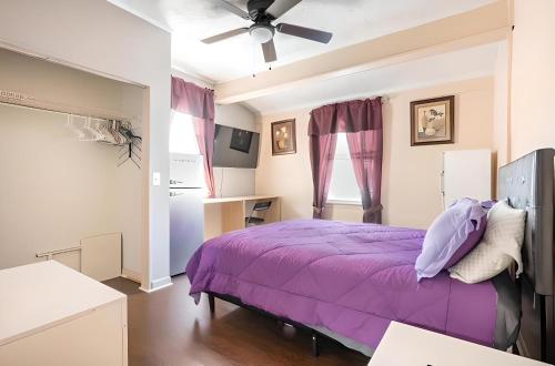 Schlafzimmer mit einem lila Bett und einem Deckenventilator in der Unterkunft Atlanta Hartsfield International Connection in Atlanta