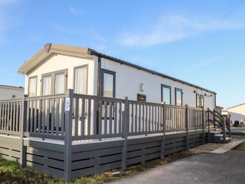 a small white house with a wooden fence at Chichester Lakeside Holiday Park in Chichester