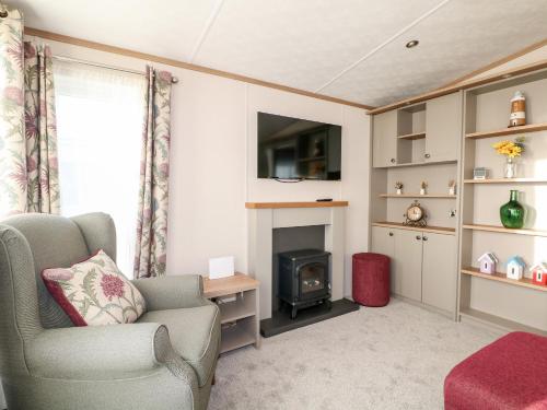 a living room with a chair and a fireplace at Chichester Lakeside Holiday Park in Chichester