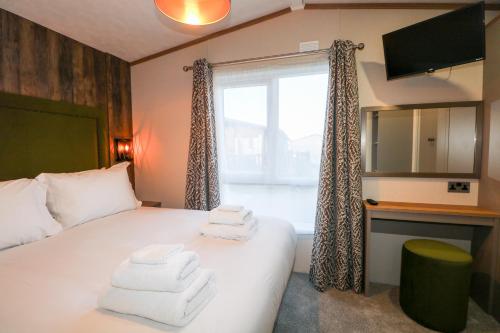 1 dormitorio con 1 cama con toallas en Chichester Lakeside Holiday Park, en Chichester