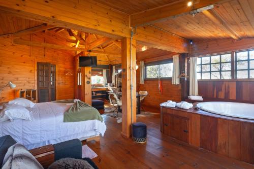 Pousada Loft da Serra في لافراس نوفاس: غرفة نوم مع سرير وحوض استحمام في غرفة