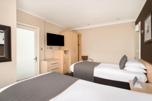 a hotel room with two beds and a television at Royal Station Hotel- Part of the Cairn Collection in Newcastle upon Tyne