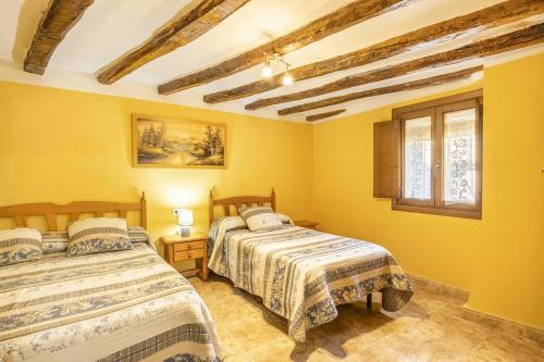 Duas camas num quarto com paredes amarelas em Casa TEULÉ em Les Iglésies