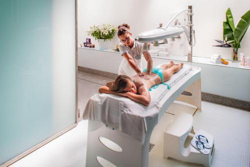 a man in a hospital room with a patient laying on a bed at Hotel Caravelle Thalasso & Wellness in Diano Marina