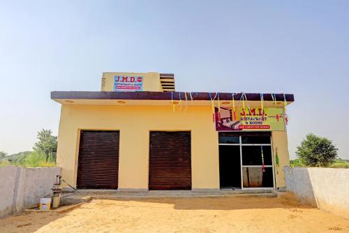 un pequeño edificio amarillo con dos puertas de garaje en OYO J.M.D Restaurant &rooms en Jhājhar