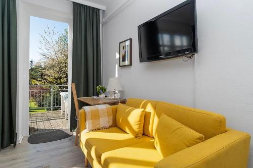 a yellow couch in a living room with a television on the wall at Ferienhof Radlandsichten in Malente