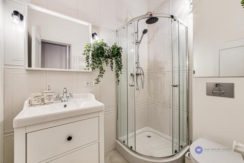 baño blanco con ducha y lavamanos en City Center Art Apartment, en Arad