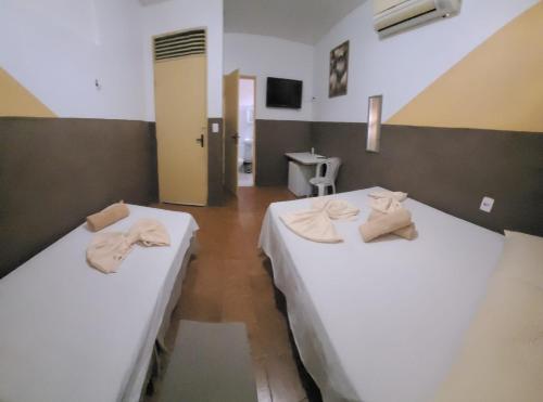 2 camas en una habitación con sábanas blancas y toallas en Pousada Descanso de Casa en João Pessoa