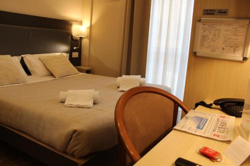 a hotel room with a bed and a desk with a phone at Hotel Victoria in Cuneo