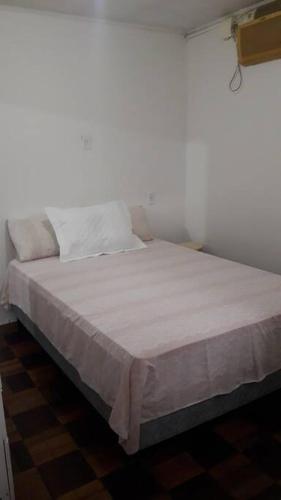 1 cama con sábanas blancas y almohadas en una habitación en Casa da Lourdes 2 quartos, en Florianópolis