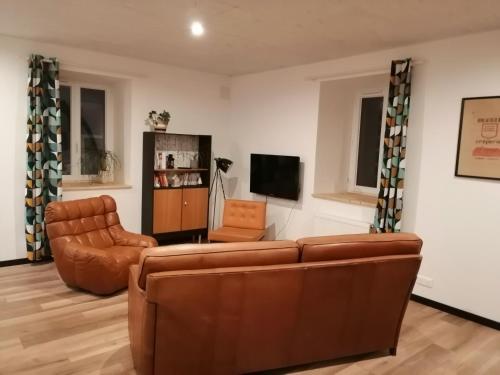 a living room with a couch and a chair at Gîte du noisetier aux Granges du Vilaret in Clairvaux-les-Lacs