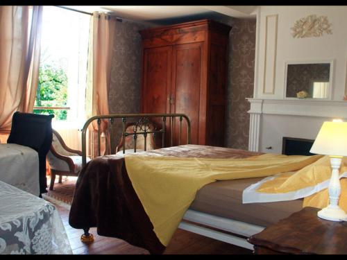 a bedroom with a bed with a yellow blanket on it at Grande maison XVIIIème avec jardin clos, ping-pong et option chambres d'hôtes - Animaux acceptés - FR-1-497-193 in Ri