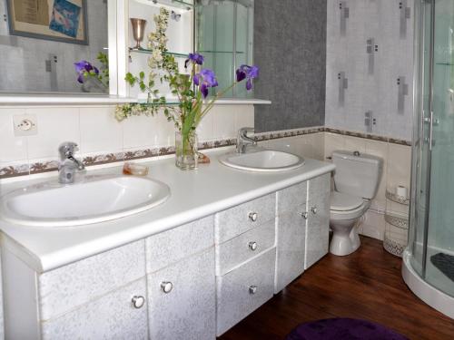 a bathroom with two sinks and a toilet with a vase of flowers at Gîte Ri, 4 pièces, 6 personnes - FR-1-497-193 in Ri