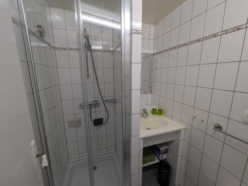 baño blanco con ducha y lavamanos en Gîte Bourbonne-les-Bains, 2 pièces, 2 personnes - FR-1-611-97, en Bourbonne-les-Bains