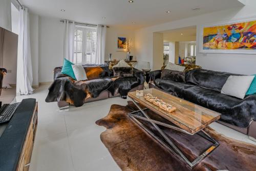 uma sala de estar com sofás de couro preto e uma mesa em Heskyn Mill Cottage em Saint Germans