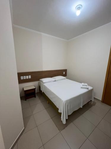 een slaapkamer met een wit bed in een kamer bij Hotel Guanabara Palace in Andradina