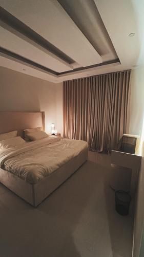 a bedroom with a bed and a window with curtains at Narcissus suite in Riyadh