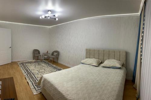 1 dormitorio con 1 cama y 1 mesa con sillas en Квартра Люкс, en Temirtaū