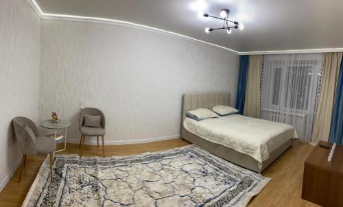 1 dormitorio con cama, mesa y alfombra en Квартра Люкс, en Temirtaū