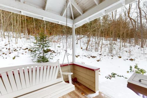 a swing on a porch in the snow at The Cave Inn in Bomoseen