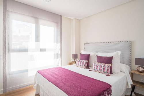 a white bedroom with a large bed with purple pillows at MALDONADO II in Madrid