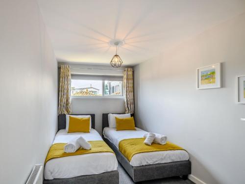 1 dormitorio con 2 camas con almohadas amarillas en 2 Bed in Mundesley KT152 en Mundesley