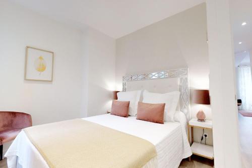 ein weißes Schlafzimmer mit einem weißen Bett und rosa Kissen in der Unterkunft FUENCARRAL II in Madrid