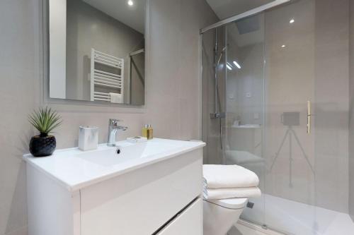 biała łazienka z umywalką i prysznicem w obiekcie FUENCARRAL II w Madrycie