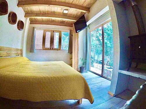a bedroom with a yellow bed and a large window at Cabaña Primavera, Acogedora cabaña en el bosque in Zinacantán