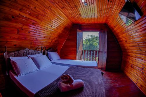 Dormitorio con cama y ventana en una cabaña de madera en Vale Encantado - Eco Park & Hotel, en Biritiba-Mirim