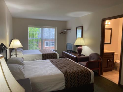 a hotel room with two beds and a window at The Hotel Pratt in Cooperstown