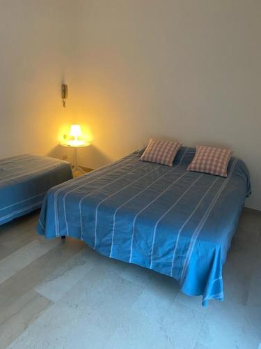 a bedroom with two beds with blue sheets and a lamp at Casa di Anna in Ravenna