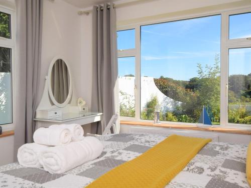 a bedroom with towels on a bed with a large window at 4 Bed in Brixham 76402 in Brixham