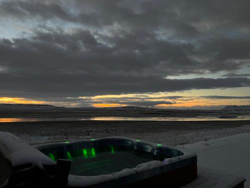 a bath tub on a beach with a cloudy sky at Luxury villa with hot tub & amazing view in Reykholt