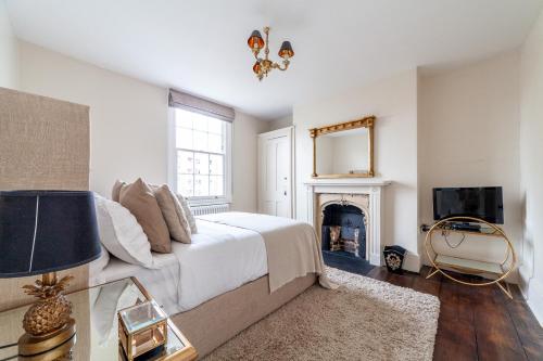 Dormitorio blanco con cama y chimenea en The New Cross Premier Rooms, en Londres