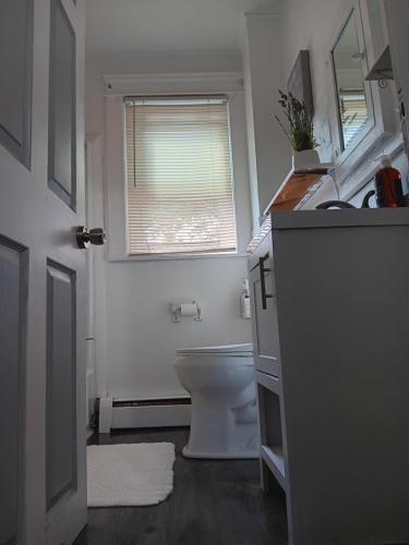 a white bathroom with a toilet and a window at The Attic Room # 1 at The North End. NEW PRIVATE ROOM near Providence College in Providence