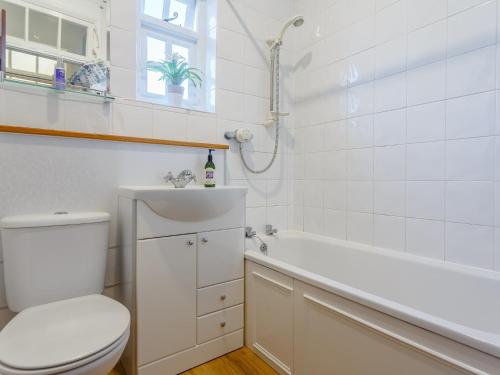 a white bathroom with a toilet and a bath tub at 2 Bed in Holsworthy 77555 in Black Torrington