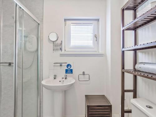 a white bathroom with a sink and a shower at 4 Bed in The Cairngorms 46162 in Tomintoul
