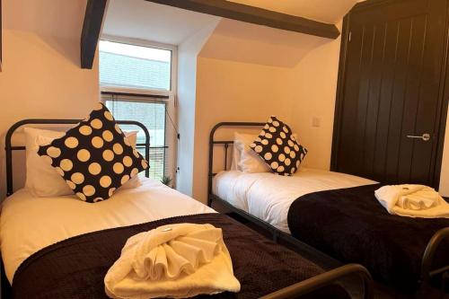 Pokój z 2 łóżkami z czarno-białymi poduszkami w obiekcie Cosy Cottage By MGroupSA w mieście Aberdare