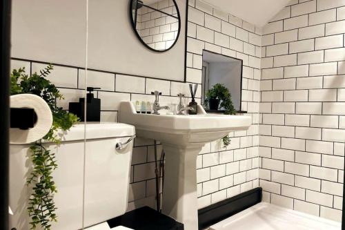 Baño blanco con lavabo y espejo en Cosy Cottage By MGroupSA, en Aberdare
