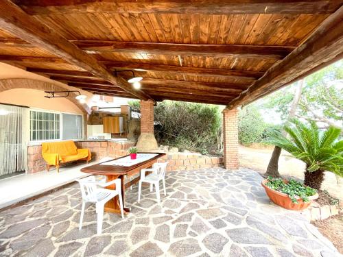 a patio with a table and chairs under a wooden roof at Tiny House Bellavista in Bari Sardo