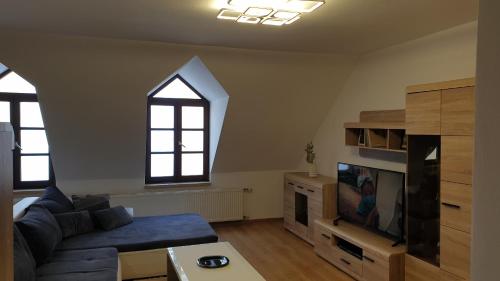 a living room with a blue couch and a tv at LINDA apartment in Trenčín