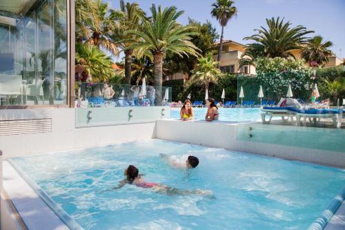 two children swimming in a swimming pool at a resort at Hotel Caravelle Thalasso & Wellness in Diano Marina