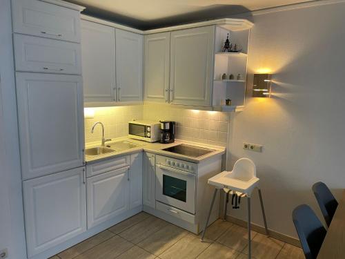 een kleine keuken met witte kasten en een wastafel bij Haus Baltic Koje 04 in Cuxhaven