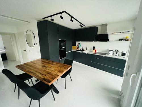 uma cozinha com uma mesa de madeira e cadeiras pretas em Moderne Wohnung nahe Museum em Sinsheim