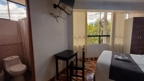 een slaapkamer met een bed, een toilet en een raam bij Qory Punku Villa Militar in Cuzco