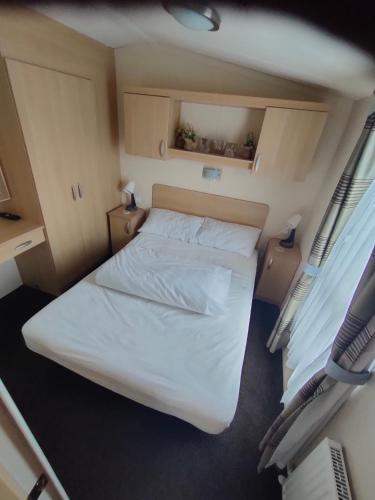a small bedroom with a bed and two windows at M&C Caravan Hire Sunnysands in Barmouth