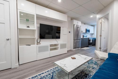 a white living room with a blue couch and a tv at Victoria's Lookout in London
